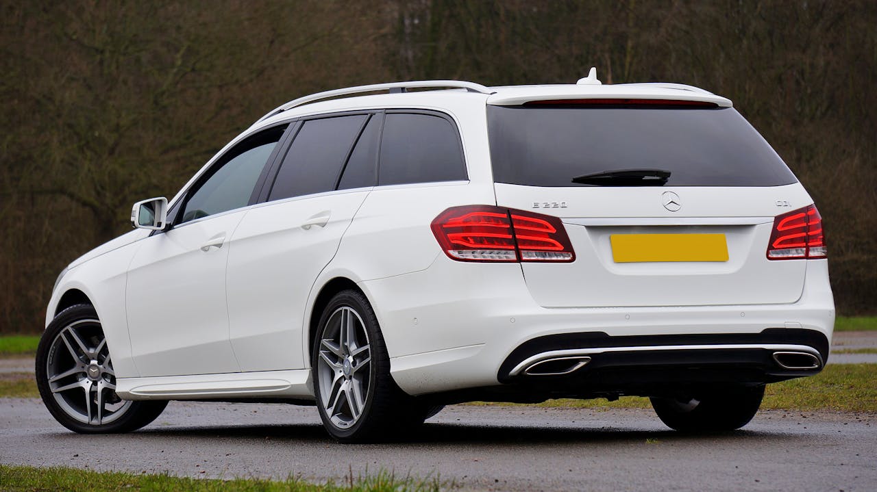 creative-03 Sleek white Mercedes-Benz E220 station wagon parked along a road, showcasing modern design and elegance.