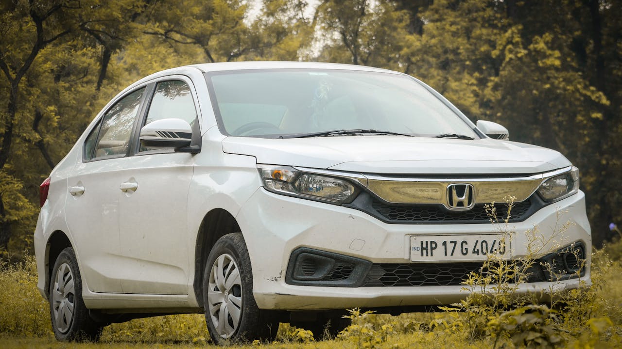 White sedan car parked outdoors with scenic foliage background.